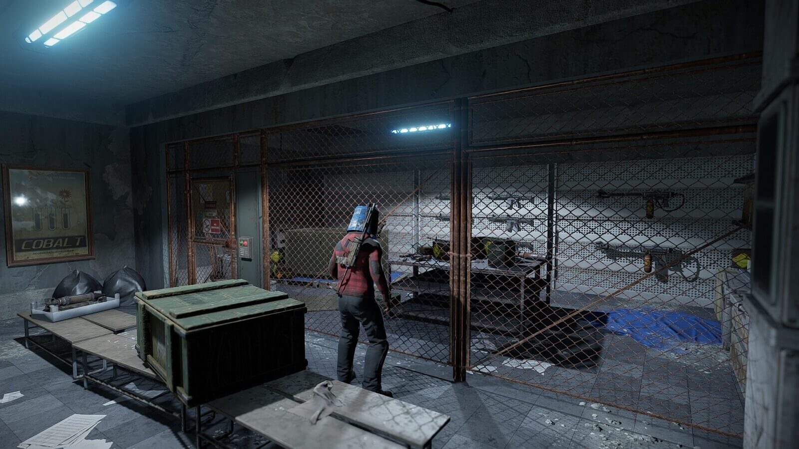 A player looting boxes in a room with a gate covering an area with a large arsenal of guns that aren't achievable to get